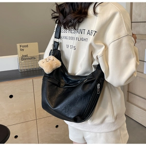 Side view of large black hobo bag with wide strap and cute beige plush pendant decoration