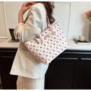 Side view of large tote bag with horse print and pink bow decoration on a desk