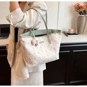 Detailed shot of large tote bag with horse print and pink bow charm in an office setting