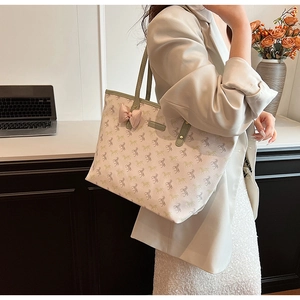 Close-up of a large tote bag featuring green horse prints and a pink satin bow detail