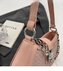 Detail of pink woven leather shoulder bag with glossy silver hardware and chain