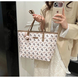 Detail of horse pattern tote bag with pink bow accessory and sturdy brown handles