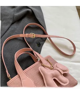 Borsa a secchiello rosa intrecciata con tracolla regolabile e ciondolo a coniglio su blazer