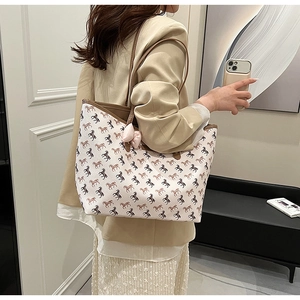 Large cream tote bag with brown horse pattern and pink bow detail worn by model