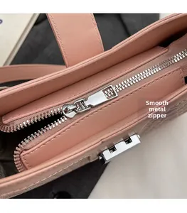 Close-up of smooth silver zipper hardware on pink woven texture shoulder bag