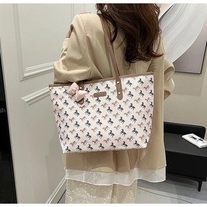 Detailed view of large tote bag with horse print and elegant pink bow charm accessory