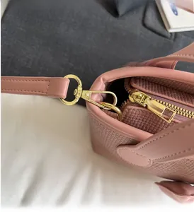 Dettaglio macro della borsa a secchiello in pelle intrecciata rosa con hardware dorato