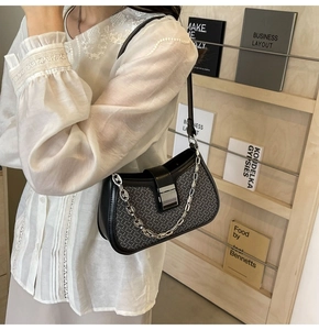 Detail of black woven underarm bag with thick silver chain and metal square lock