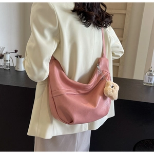 Pink PU leather hobo bag with teddy bear pendant shown on model in a modern room