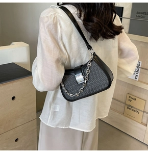 Close-up of black woven leather shoulder bag featuring stylish silver chain and metal clasp
