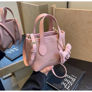 Dettaglio della borsa a secchiello rosa chiaro con logo in metallo e charm cane in pelle