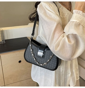 Detail of black woven PU leather shoulder bag with bold silver chain and metal buckle