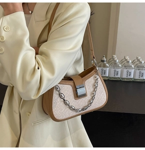 Detail of woven cream fabric and brown leather edge on a stylish underarm bag