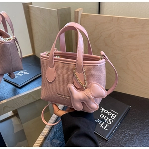 Dettaglio mini borsa a secchiello rosa con trama intrecciata e ciondolo a cane