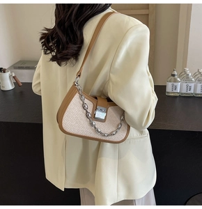 Detail of white crocodile embossed underarm bag with silver chain and metal lock