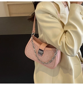 Detail of pink woven shoulder bag with silver chain and metal clasp on beige blazer