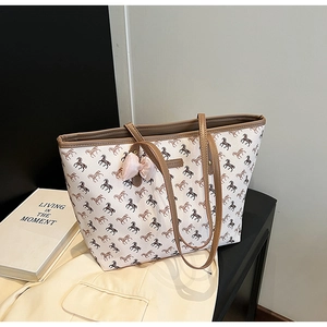 Detail of printed tote bag with horse patterns and a pink satin bow accessory