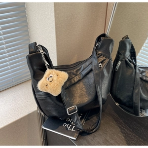 Macro detail of black PU leather dumpling bag with textured finish and cute bear pendant