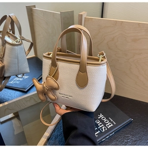 Dettaglio della mini borsa a secchiello intrecciata con finiture in pelle marrone