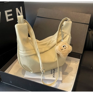 Macro shot of cream hobo bag with soft PU leather texture and plush bear charm detail