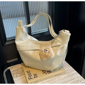 Detail of hobo bag in cream PU leather with soft pleats and plush smiley charm