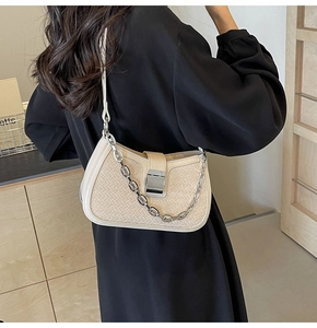 Detail of beige woven texture shoulder bag with silver chain and metal clasp