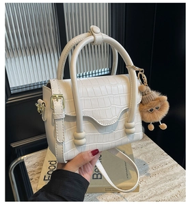 Detailed shot of white crocodile embossed PU leather bag with a cute plush bear pendant