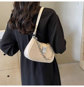Close-up of cream woven hobo bag featuring silver chain and metal lock on a model