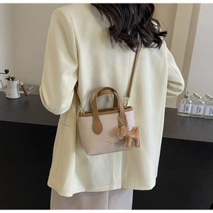 Dettaglio di una borsa a secchiello in tessuto minimalista con finiture in pelle marrone