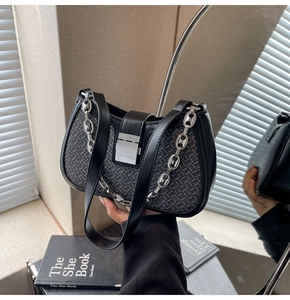 Detailed view of black woven texture shoulder bag with silver chain and metal clasp