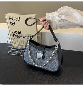 Detail of grey woven underarm bag featuring silver chain and sleek metal clasp