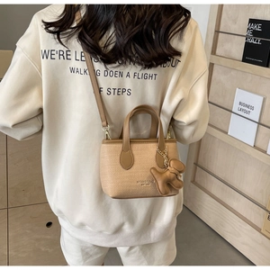 Dettaglio della borsa tote beige in tessuto con ciondolo a forma di cane e tracolla