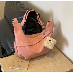 Detail of peach pebbled leather crossbody bag with cute plush smiley charm on stone base