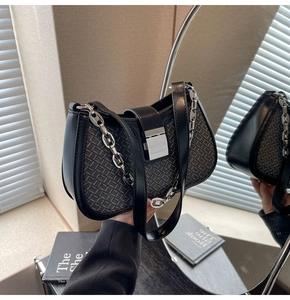Detailed mirror view of black woven shoulder bag with silver chain and metal buckle