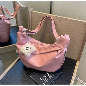 Detailed view of pink leather half-moon bag with pockets and cute plush charm pendant