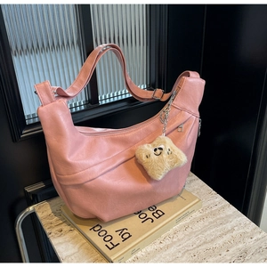 Pink crescent hobo bag detail with adjustable strap and plush smiley face charm