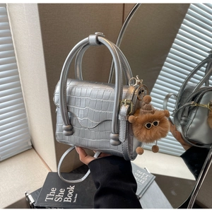 Detail of silver crocodile-embossed mini square bag with a plush bear charm decoration