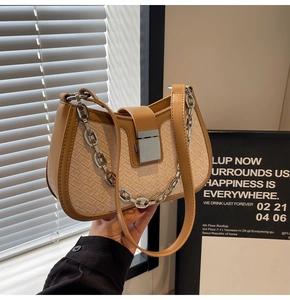 Detail of woven beige shoulder bag with tan leather trim and silver metal chain strap