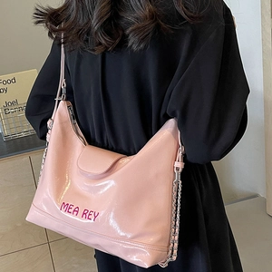 Borsa tote rosa in similpelle con ricamo MEA REY e tracolla a catena indossata da modella