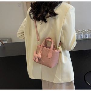 Vista dettagliata della borsa a secchiello rosa intrecciata con logo MIKAZU BAG e charm