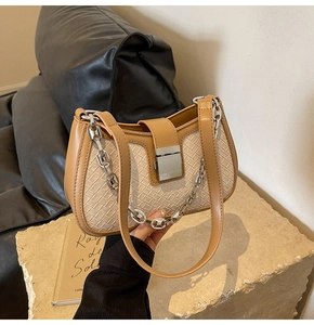 Close-up of brown leather and beige woven fabric underarm bag with silver chain