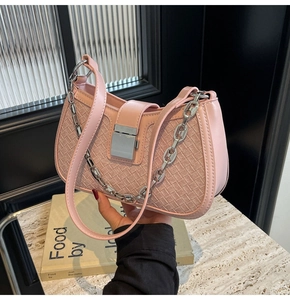 Detail of pink woven underarm bag featuring silver chain and metal lock closure