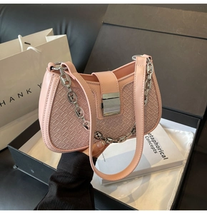Close-up of pink leather underarm bag featuring woven texture and silver metal lock