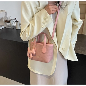 Borsa a secchiello rosa intrecciata con ciondolo a cucciolo e tracolla rimovibile