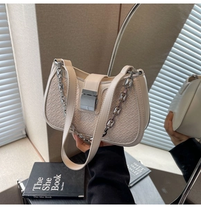 Detailed view of beige woven texture shoulder bag with silver chain and flap closure