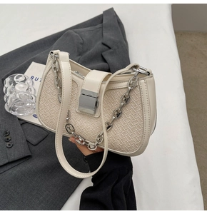 Detailed view of cream woven crossbody bag with chunky silver chain and metal clasp