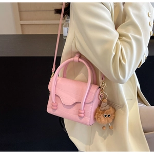Pink crocodile-textured handbag with a cute plush charm accessory for women's crossbody wear