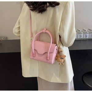 Pink croc-embossed small crossbody bag with a wavy flap and cute plush doll charm