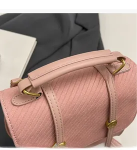 Détail d'un sac à main rose en similicuir avec poignée renforcée et anneaux métalliques dorés