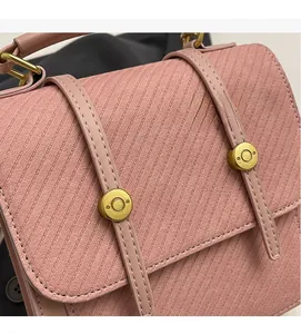 Gros plan sur la texture du tissu rose et les boucles dorées de ce sac à main chic